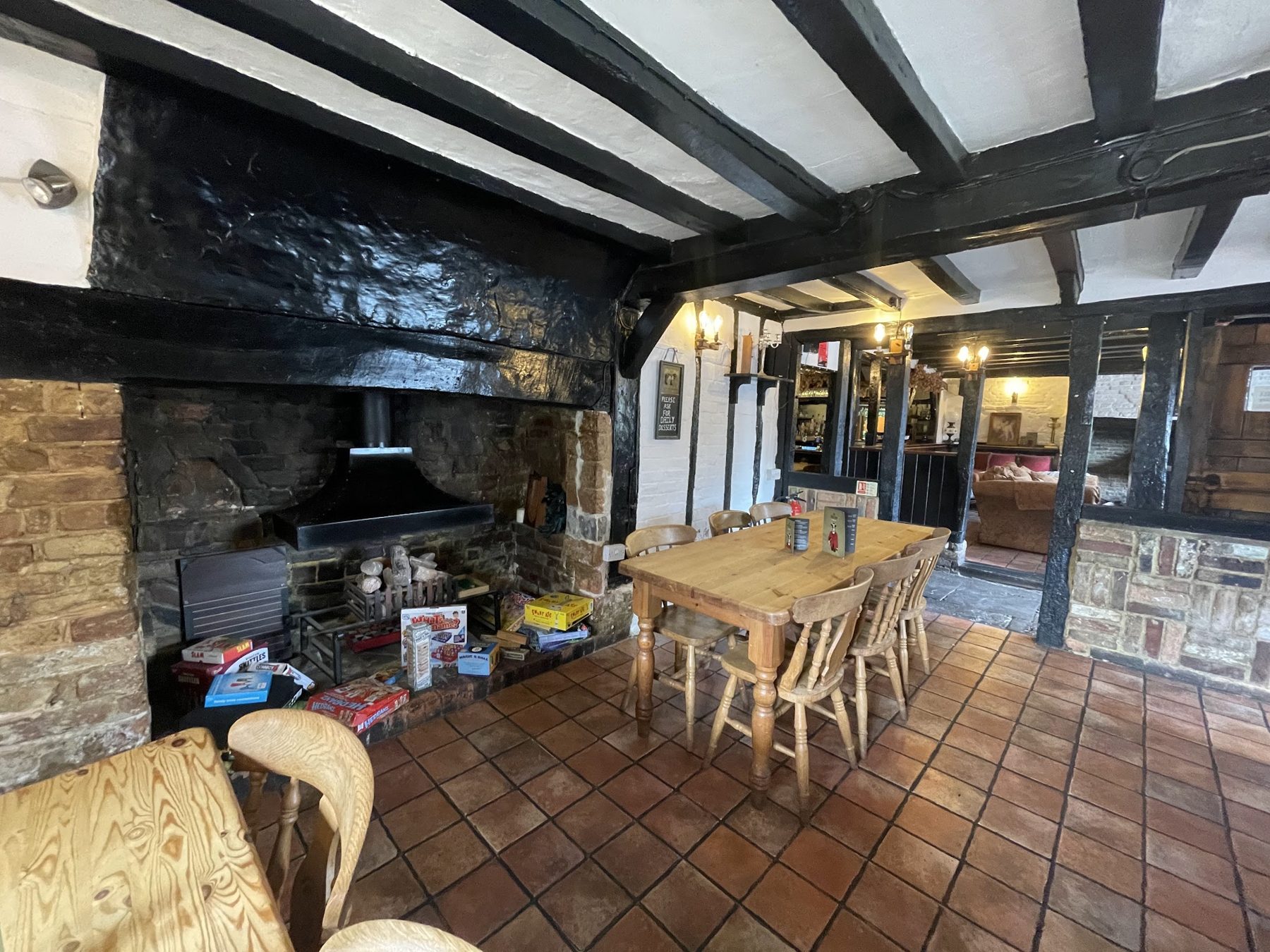 The beamed room with a large open fireplace and wooden tables