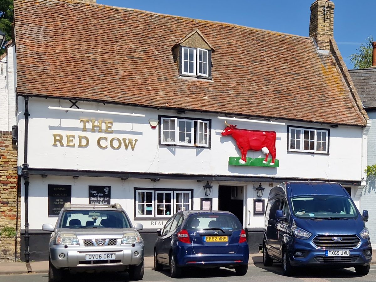 The white pub with a tiled roof and a red cow on the THE RED COW sign